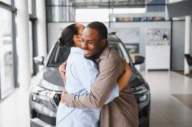 Heyecanlı çift, bir galeriden yeni bir araba alıp birbirlerine olan sevgilerini ve başarılarını kutladıktan sonra sevinçle kucaklaşıyorlar.