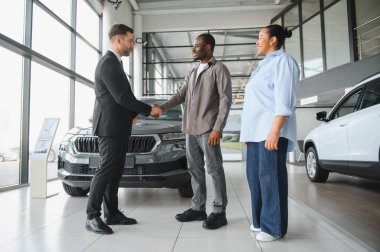 Araba satıcısı, Afro-Amerikan bir adamla el sıkışıyor. Bir galeriden yeni bir araba alıyor, anlaşma yapıyor.