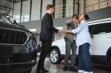 Araba satıcısı, mutlu bir Afrikalı Amerikalı çifte yeni bir araba almak için belgeleri teslim ediyor.