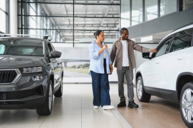 Afrika kökenli Amerikalı çift otomobil galerisinde yeni SUV arabalarını inceliyor, otomobil almakla ilgili karar veriyorlar.