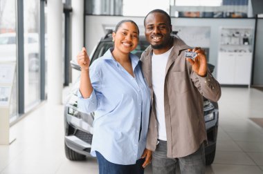Galeride yeni araba alımlarını kutlarken anahtar gösteren heyecanlı çift