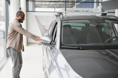 Mutlu müşteri, heyecan ve gururla dolu bir galeride yeni bir arabanın kapısını açıyor.