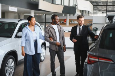 Araba satıcısı, bir araba galerisinde Afro-Amerikan bir çifte yeni bir araba sunuyor. Hayallerindeki aracı seçmek için yardım ve rehberlik öneriyor.