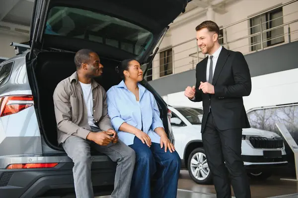 Araba satıcısı, galeriden yeni bir araba almak isteyen bir çifte araç sunuyor.