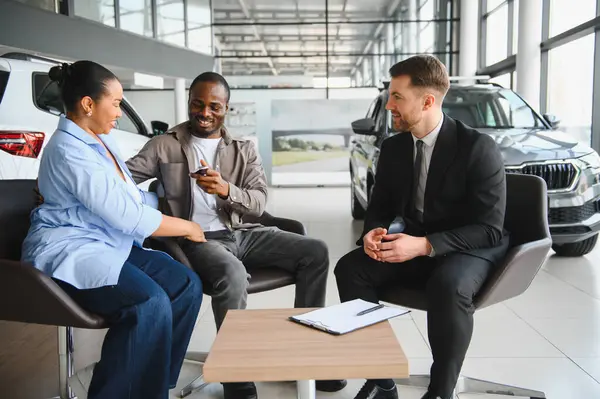 Modern bir galeride yeni bir araba seçerken Afrikalı Amerikalı çift bir satıcıya danışıyor.