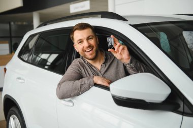 Satıcıda yeni arabasında oturan mutlu adam, yeni alımı için heyecanlı.