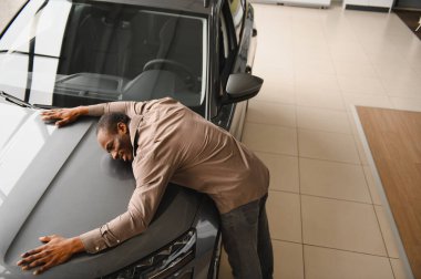 Galeride yeni gri arabasını kucaklayan heyecanlı bir müşteri satın alımını neşe ve memnuniyetle kutluyor.