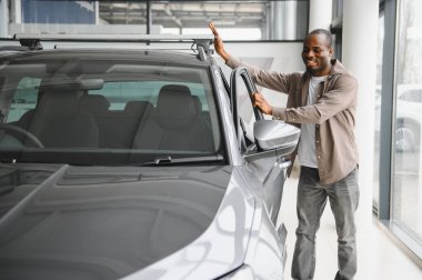 Bir galeride yeni arabasına hayran olan mutlu bir müşteri son satın alma ve yatırımıyla ilgili heyecanlı ve gururlu.