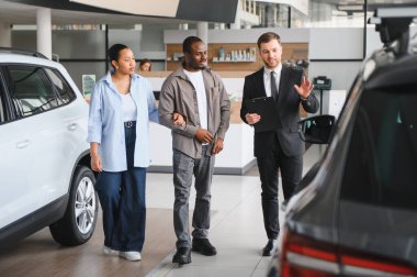 Araba satıcısı, modern bir galeride Afro-Amerikan bir çifte profesyonel yardım ve rehberlik sunuyor.