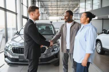 Satış elemanı Afrikalı Amerikalı bir çiftle el sıkışıyor. Bir galeriden yeni bir araba alıyorlar. Başarılı bir anlaşma yapıyorlar.