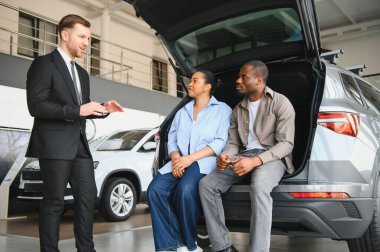 Araba satıcısı, açık sandıkta oturan ve kargo alanı ve pratik konularını tartışan Afro-Amerikan çifte araç özelliklerini sunuyor.