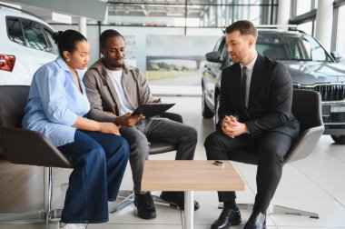 Afrika kökenli Amerikalı bir çift, bir araba satıcısıyla olan sözleşmelerini inceliyor. Modern bir galeride yeni bir araç satın alma potansiyeli var.