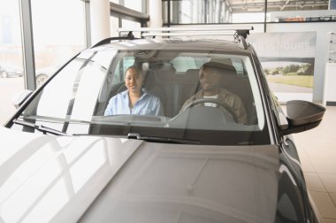 Gülümseyen Afro-Amerikan çift yeni bir arabayı galeride test ediyor. Satın almaya hazır.