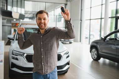 Heyecanlı müşteri yeni araba alımını kutluyor. Canlı bir galerinin anahtarlarını elinde tutuyor.