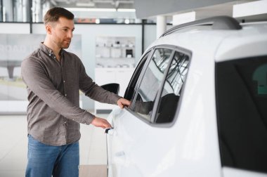 Galeride yeni bir beyaz arabanın kapısını açan adam test sürüşüne hazırlanıyor ve önemli bir satın alma kararı veriyor.