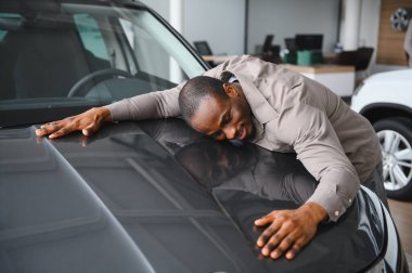 Galeride yeni arabasını kucaklayan heyecanlı müşteri, son satın alımından mutluluk ve memnuniyet yayıyor.