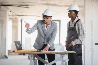 İnşaat aşamasında binayı işaret ederken, mimarın inşa planlarını açıklamasıName