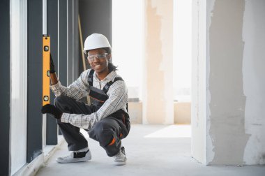 Afrika kökenli Amerikalı inşaat işçisi inşaat sırasında tam olarak dikey hizalama sağlamak için ruh seviyesini kullanır.