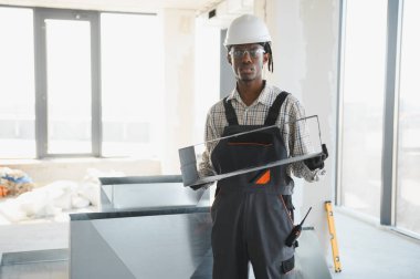 İnşaat halindeki bir binaya havalandırma sistemi kuran Afrikalı Amerikalı inşaat işçisi, en uygun iklimi ve konforu sağlıyor.