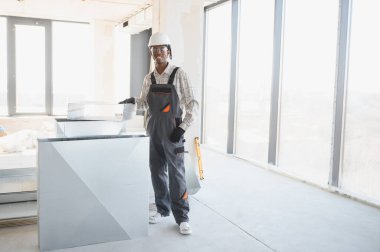 Afrika kökenli Amerikalı inşaat işçisi inşaat halindeki bir binaya havalandırma sistemi kuruyor, güvenlik ve hassasiyete odaklanıyor.