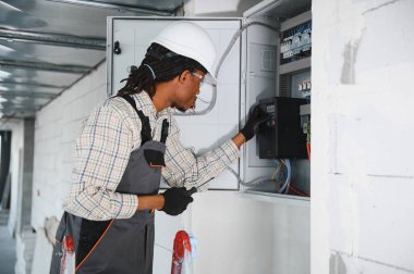 Elektrikçi inşaat halindeki bir binaya havalandırma sistemi kontrol paneli kurarak uygun hava akışını ve iklim kontrolünü sağlıyor.