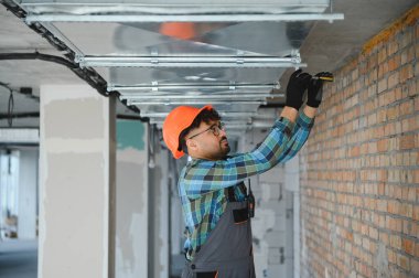 Arap mühendis inşaat sahasına havalandırma sistemi kuruyor. Metal hava kanalları üzerinde ustalıkla çalışıyor ve uygun hava akışını sağlıyor.
