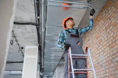 Bir inşaat sahasında havalandırma sistemi kurulumu üzerinde çalışan Arap mühendis düzgün bir hava akışı ve işlevsellik sağlıyor