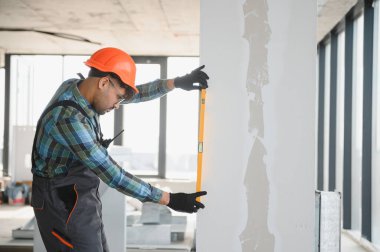 İnşaat sırasında duvarın dikey görünmesini sağlamak, geliştirme projesinde hassasiyet ve kalite kontrolünün vurgulanması için ruh seviyesini kullanan odaklanmış mühendis