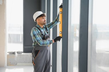 İnşaat sırasında pencere çerçevesinin dikey hizalanmasını sağlayan ruh seviyesini kullanan Arap inşaatçı