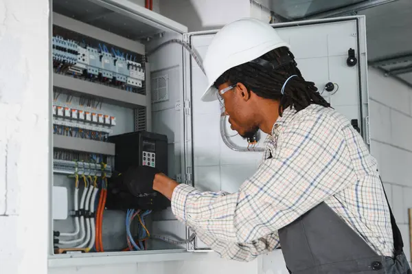 Elektrik paneli üzerinde çalışan elektrikçi inşaat halindeki bir binaya havalandırma kontrol paneli yerleştiriyor.