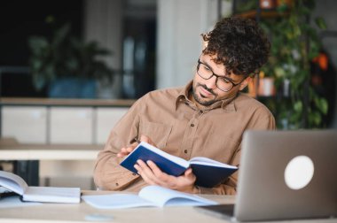 Üniversite kütüphanesinde okurken ders kitaplarından notlar alan genç Arap öğrenci, akademik başarı ve öğrenmeye odaklandı