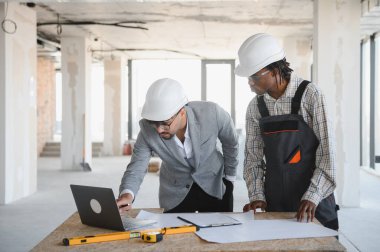 İnşaat halindeki bir binaya yapılan ziyarette dizüstü bilgisayarın planlarını gözden geçiren mimar ve mimar.