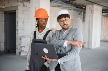 İnşaat teftişi sırasında inşa etmek için dizüstü bilgisayarda bina planını gösteren mimar, ilerleme ve sonraki adımları tartışıyor