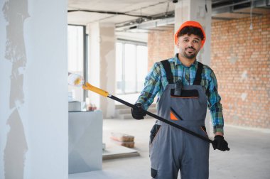 İç duvarları teleskopik boya silindiriyle boyayan bir Arap müteahhit, bir inşaat sahasında ev yenileme projesiyle meşgul.