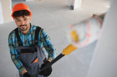 Arap inşaat işçisi, bir yenileme projesi üzerinde çalışarak, uzun bir fırça kullanarak duvar boyuyor.