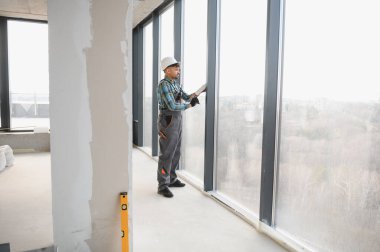 Modern binadaki pencere çerçevesini kapatan inşaat işçisi.