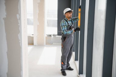 Arap inşaat işçisi, yoğun bir şantiyedeki yapıları ölçerken ve hizalarken hassas bir doğruluk sağlıyor.