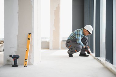 İnşaat işçisi inşaat halindeki bir binanın pencere çerçevelerine dolgu macunu sürüyor, hava geçirmez ve hava geçirmez kurulumunu sağlıyor