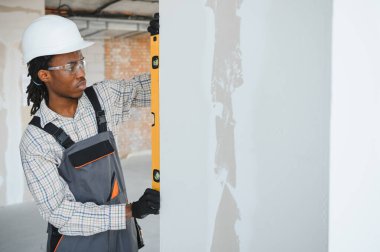 İnşaat alanında düz bir araç kullanan Afrikalı Amerikalı inşaatçı, inşaat sürecinde tam olarak dikey hizalama sağlıyor