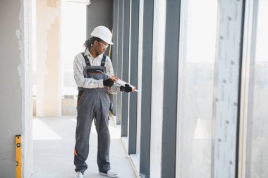 Profesyonel inşaat işçisi yeni inşa edilmiş bir binanın penceresine dolgu macunu sürüyor, hava geçirmez ve hava geçirmez yalıtım sağlıyor.