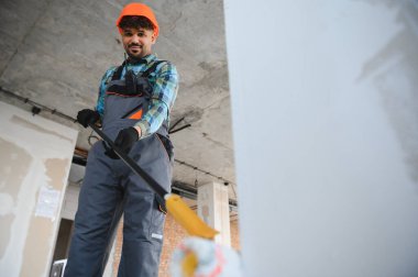 Bir inşaat sahasında ölçüm aracı kullanan Arap inşaat işçisi, inşaat projesi için kesin ölçümler sağlıyor