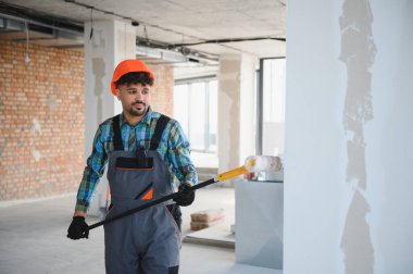 Bir inşaat sahasında duvarları uzun bir silindirle boyayan Arap mühendis, bir yerleşim alanının içini dönüştürmeye odaklanmış.