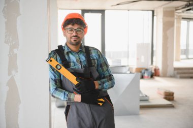 Genç Arap mühendis inşaat alanında dikilirken başlık takıyor ve ruh seviyesini koruyor.