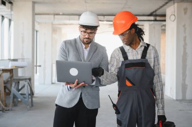 İnşaat alanı teftişi sırasında bir mimarın dizüstü bilgisayarında bina planlarını göstermesi