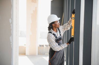 İnşaat sırasında pencere çerçevesinin tam olarak dikey hizalanmasını sağlamak için ruh seviyesini kullanan Afrikalı Amerikalı inşaatçı
