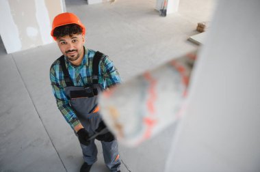 Arap mühendis inşaat halindeki bir binanın içine duvar yapıştırıyor, profesyonel aletler kullanıyor ve güvenlik ekipmanları takıyor.