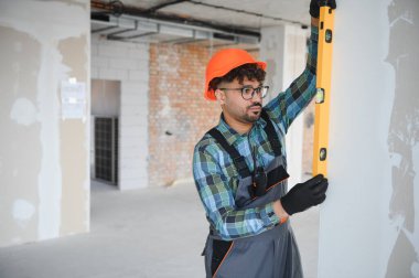 Odaklanmış mühendis, duvarın yüksekliğini ruh seviyesiyle özenle kontrol ederek, devam eden inşaatın ortasında hassasiyet ve yapısal bütünlüğü sağlıyor.