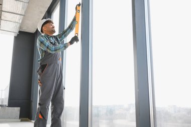 İnşaat sırasında pencere çerçevesini sağlamak için ruh seviyesi kullanan Arap inşaatçı mükemmel bir şekilde dikey