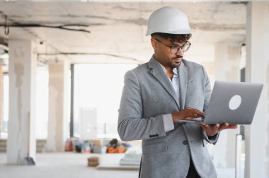 İnşaat alanında dizüstü bilgisayar kullanan, proje geliştirmeyi denetleyen ve inşaat sürecini yöneten Arap mimar