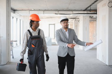 İnşaat halindeyken Afrikalı Amerikan inşaatçılara planlar gösteren Arap mimar.